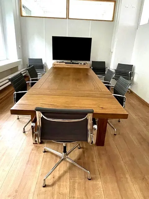 Konferenzraum mit grossem Holztisch und Bildschirm